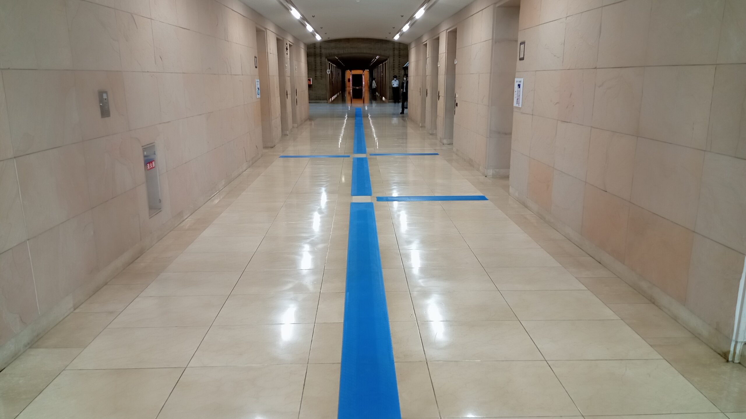 A blue hodokun has been installed in the centre of a wide corridor and is used to guide people to the toilets and lifts.